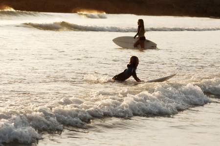 surfer boy watches a surfer girl in the sea in Galicia Beach Doninhosの写真素材