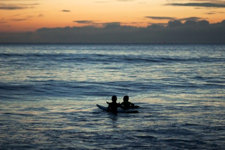 two surfers children talking at sea at dusk in Doninhos Galicia Beachの写真素材