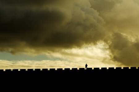 man walking silhouette at sunset with clouds in stormy day