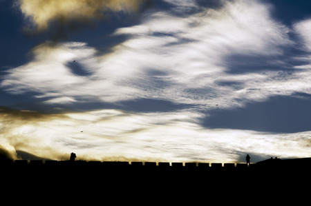 people walking silhouette at sunset with blue sky and cloudsの写真素材