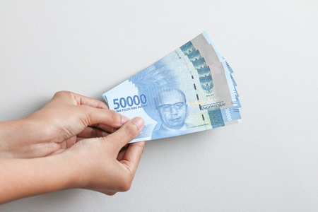 hand holding rupiah Indonesian moneyの写真素材