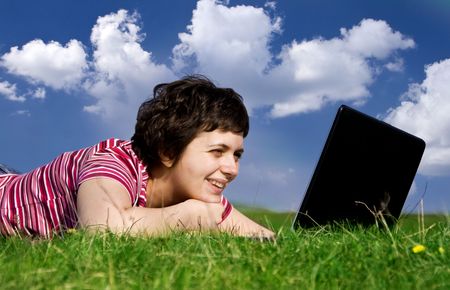 Young casual woman working on laptop outdoorsの写真素材