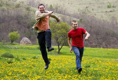 Young attractive men jumping in summer fieldの写真素材