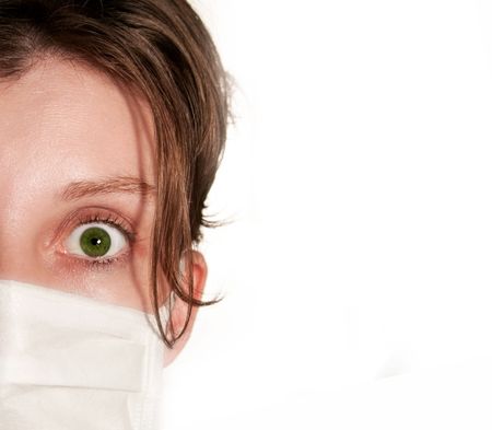Woman with big green eyes wearing medical mask protecting against flu virusの写真素材