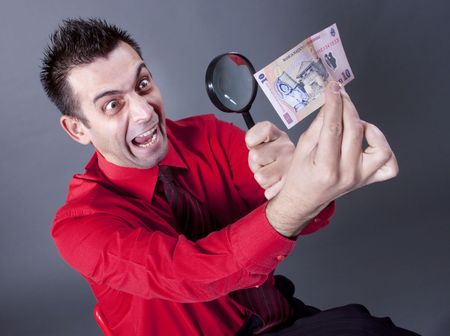 Funny businessman looking at banknote with magnifying glassの写真素材