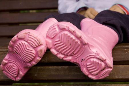 Pink waterproof boots on little girl's legs の写真素材
