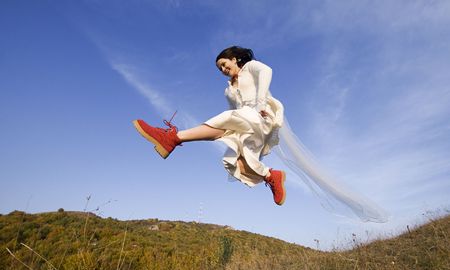 Happy bride with red boots jumping highの写真素材