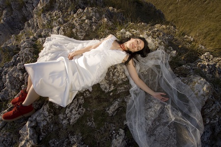 Beautiful bride posing on rocks in high mountain scenery の写真素材
