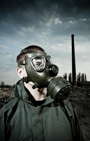 Bizarre portrait of man in gas mask on smoky industrial background with pipes after nuclear disaster の写真素材