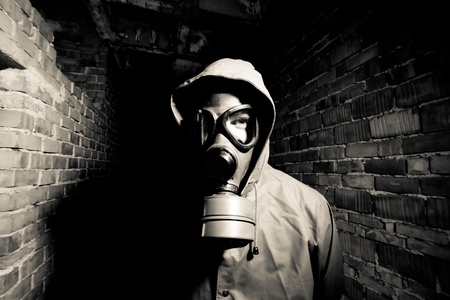 Bizarre portrait of man in gas mask on smoky industrial background with pipes after nuclear disaster の写真素材