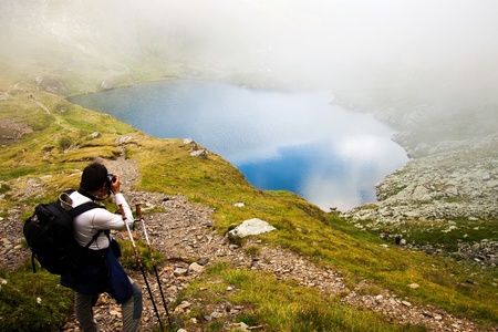 Hiker taking photos at Capra lake in Fagaras mountains, Romaniaの写真素材