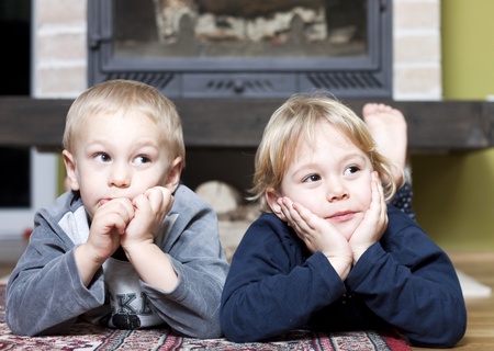 Siblings on floor looking at something の写真素材