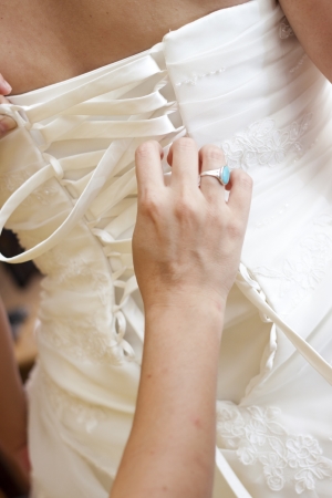 hands helping with bride s white corset の写真素材