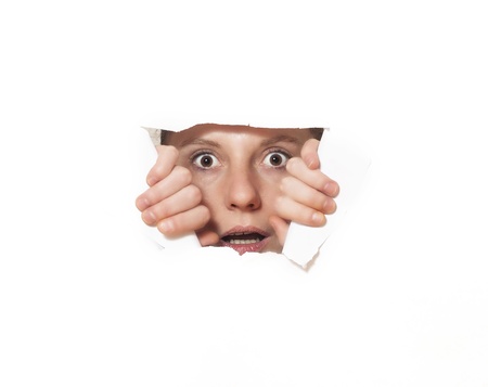 Young woman looking through torn paper hole