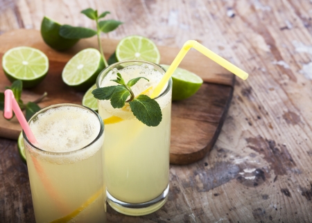 Fresh limes and lemonade on wooden backgroundの写真素材