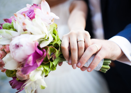 Hands and rings on wedding bouquetの写真素材