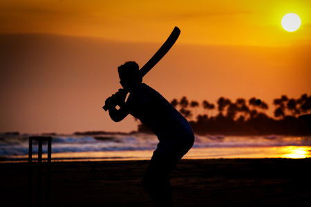 Boy playing cricket at sunset on tropical beach in Sri Lankaの写真素材
