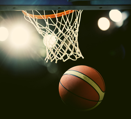 Basketball going through the hoop at a sports arenaの写真素材