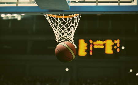 Basketball going through the hoop at a sports arenaの写真素材