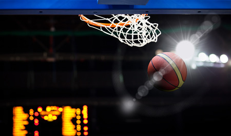 Basketball going through the hoop at a sports arenaの写真素材