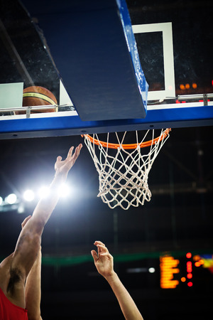 Basketball going through the hoop at a sports arenaの写真素材