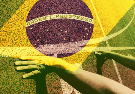 Hands on starting line - running track and Brazil flag