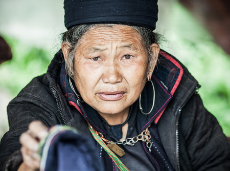 SA PA, VIETNAM - AUGUST 2017: Portrait of black hmong ethnic minority woman selling goods and sewing at the market in Sa Pa town, the high mountains, Lao Cai province, Vietnamのeditorial素材