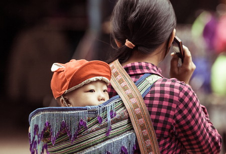 SA PA, VIETNAM - AUGUST 2017: Black hmog ethnic minority woman carrying her child in Sa Pa town, the high mountains, Lao Cai province, Vietnamのeditorial素材