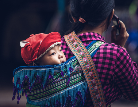 SA PA, VIETNAM - AUGUST 2017: Black hmog ethnic minority woman carrying her child in Sa Pa town, the high mountains, Lao Cai province, Vietnamのeditorial素材