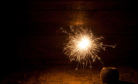 burning sparkler and christmas lights on wooden backgroundの写真素材