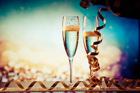 two champagne glasses against holiday lights and fireworks - new year celebrationの写真素材