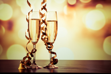two champagne glasses with ribbons against holiday lights and fireworks - New Year celebrationsの写真素材