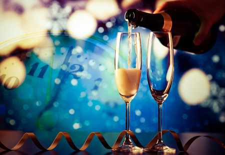 pouring champagne into glasses against holiday lightsの写真素材