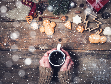 woman's hand holding mug of mulled wine and Christmas decorations on wooden backgroundの写真素材