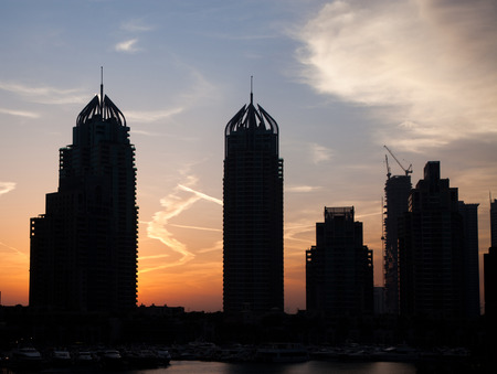 DUBAI, UAE - FEBRUARY 2018: Silhouettes of modern skyscrapers shining in sunrise lights  in Dubai Marina in Dubai, UAE.のeditorial素材