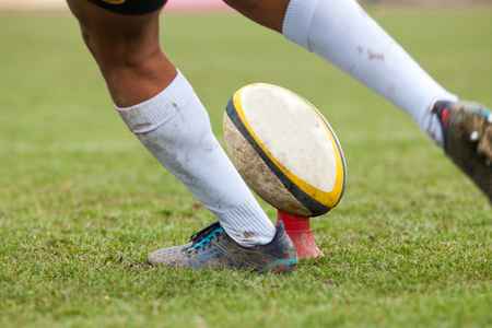 rugby player preparing to kick the oval ball during gameの写真素材