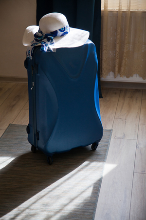 packed blue suitcase in room and straw hat ready for the summer holidayの写真素材