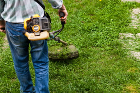 man cutting grass in garden with the weed trimmerの写真素材