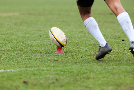 rugby player preparing to kick the oval ball during gameの写真素材