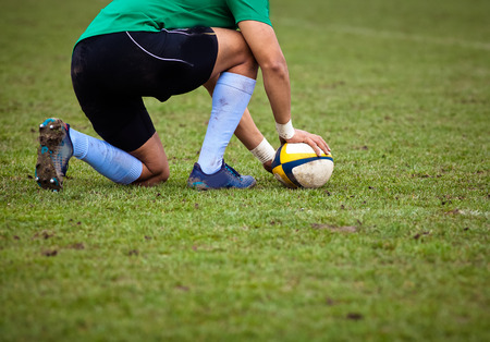 rugby player preparing to kick the oval ball during gameの写真素材