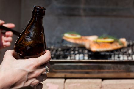 bottle of beer in man's hands while making barbecueの写真素材