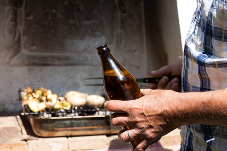 bottle of beer in man's hands while making barbecueの写真素材