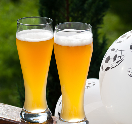two glasses of beer and balloon with footballs - watching soccerの写真素材