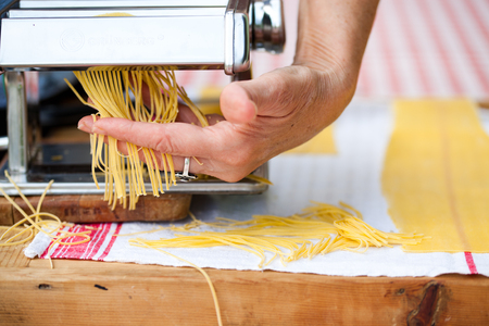 woman's hands cutting home made pastaの写真素材