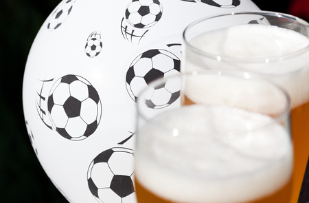 two glasses of beer and balloon with footballs - watching soccerの写真素材