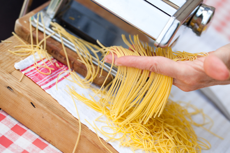 woman's hands cutting home made pastaの写真素材