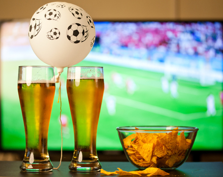 beer glasses and chips in front of tvの写真素材