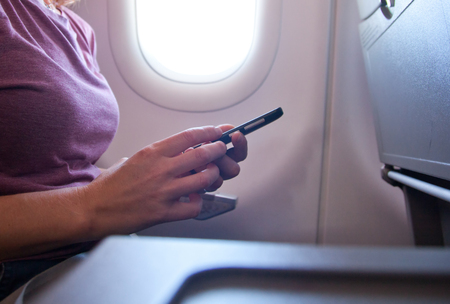 woman using smartphone on airplaneの写真素材