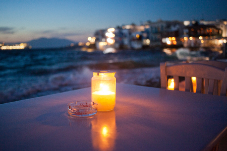 romantic table with burning candle by the sea at nightの写真素材