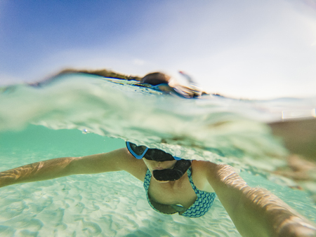 woman taking an underwater selfie while snorkeling in crystal clear tropical waterの写真素材